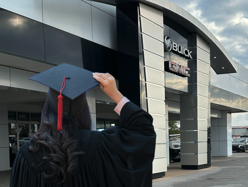 Graduate in cap and gown standing outside Crain Buick GMC in Springdale, Arkansas